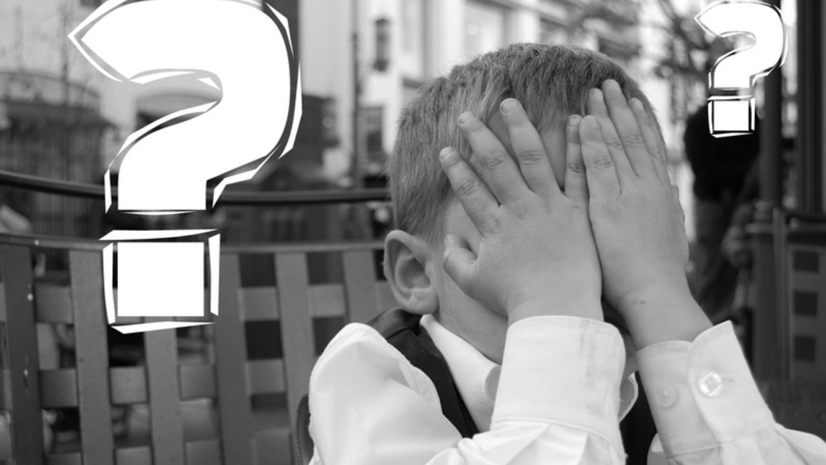 A little boy covering his eyes with his hands and a big question mark.