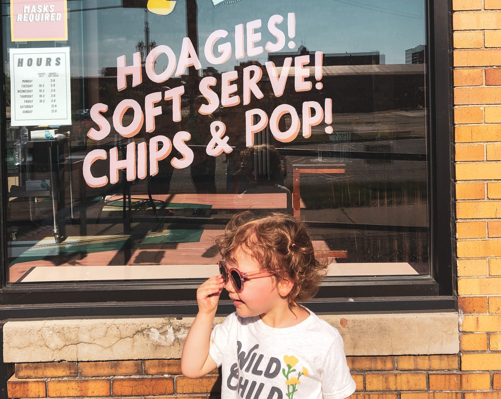 child in front of ice cream shop sign