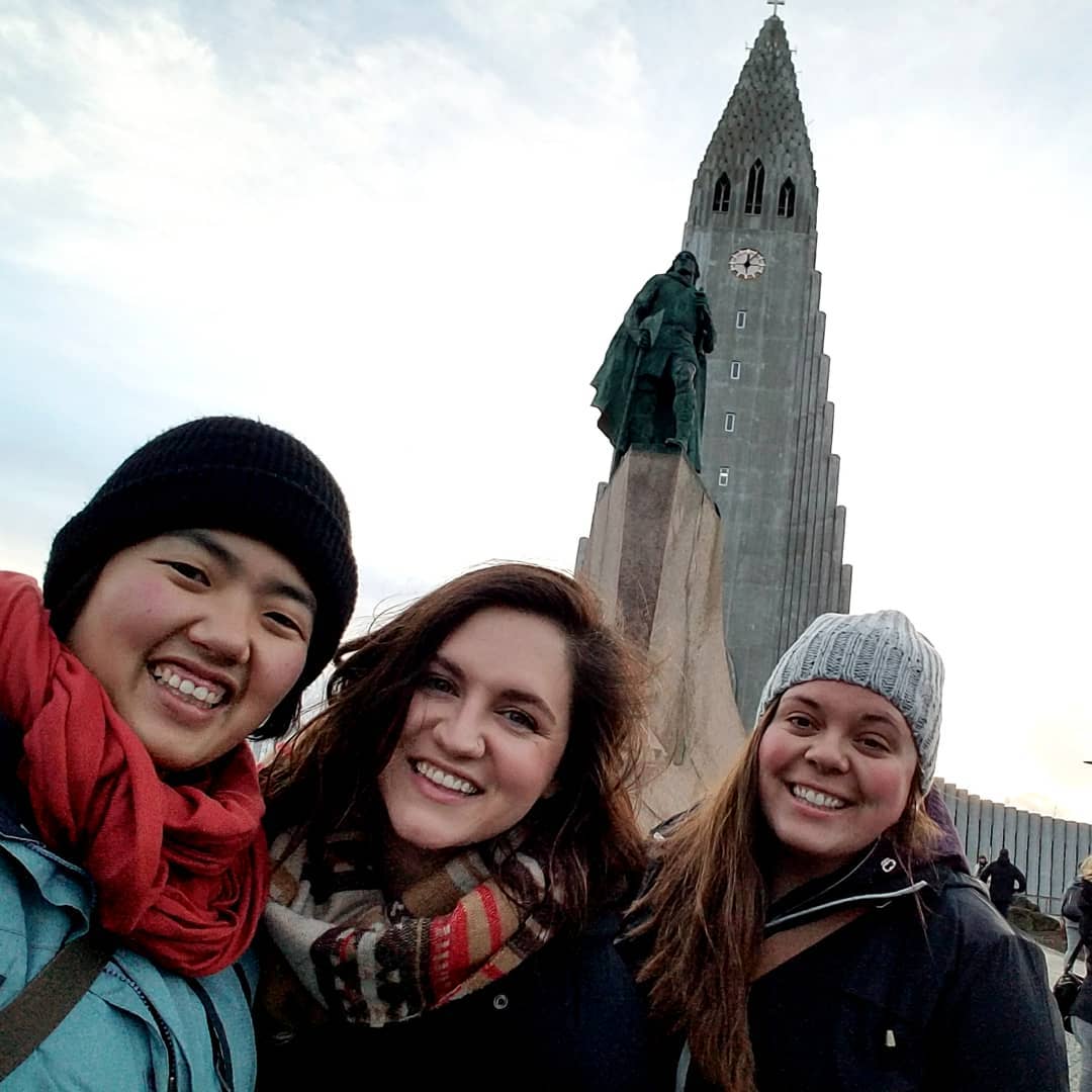 three women pose in front of tall church building