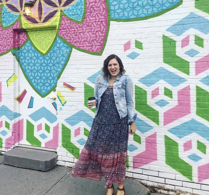woman posing in front of mural