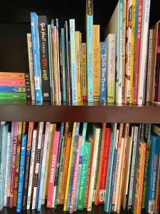 Shows bookshelf full of different colored picture books. 