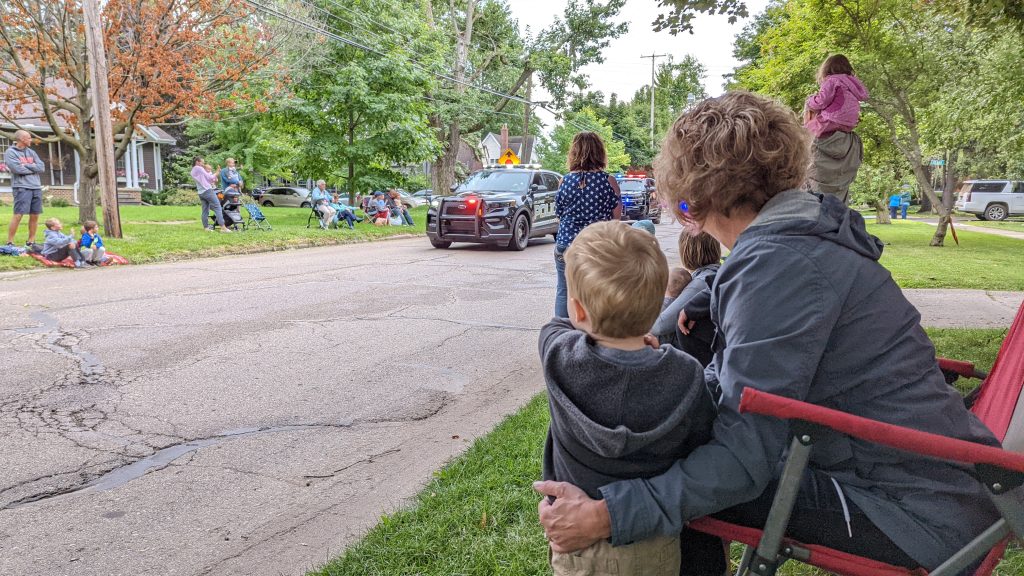 A little boy watches a parade with his aunt.